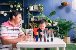 Parent sitting homeschooling with little kid, Father and son having fun preparing easy science experiment